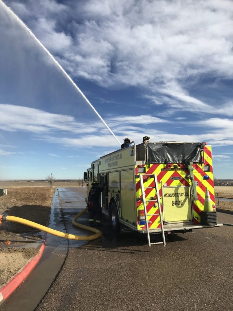 Fire engine #3901 shooting water across a field to reach a brush fire